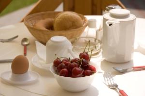 a table with a bowl of cherries and a basket of bread at Erika Pension in Keszthely