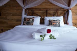 Una cama con dos almohadas y una rosa. en Living Waters Resort en Jinja