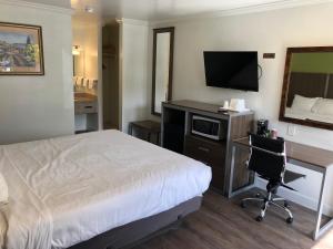 a hotel room with a bed and a desk with a television at Gilroy Inn in Gilroy