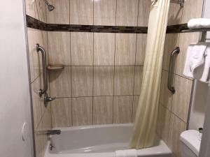 a bathroom with a tub and a shower curtain at Gilroy Inn in Gilroy