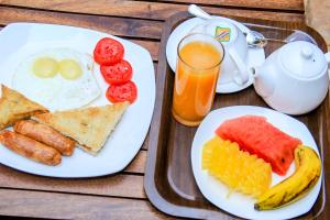 a wooden table with two plates of breakfast food at Explorers Hub in Kampala