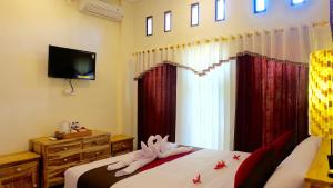 a bedroom with two beds with red curtains and a television at Wiki Bali in Ubud