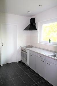 cocina con armarios blancos, fregadero y ventana en Work & Stay Sankt Augustin en Sankt Augustin