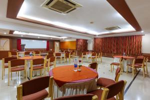 un salón de banquetes con mesas y sillas en una habitación en Hotel Woodland Kolhapur, en Kolhapur