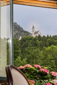 a view of a castle from a window with flowers at Chalet Villa Ludwig in Schwangau +3 photos
