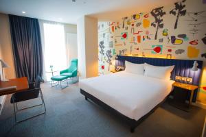 a bedroom with a large white bed and a desk at IBIS Styles Ulaanbaatar Polaris in Ulaanbaatar