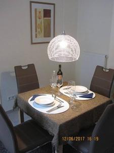 a table with plates and a bottle of wine and a lamp at Haus Harmonie in Bad Driburg