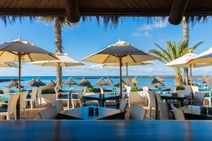 a restaurant with tables and umbrellas on the beach at Hotel Cleopatra Palace in Playa de las Americas