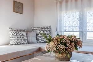 a living room with a couch and a vase of flowers on a table at Villa Thea in Panormos Skopelos