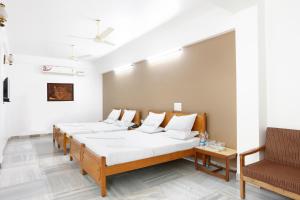 a room with three beds and a chair at Sri Aarvee Hotels in Coimbatore