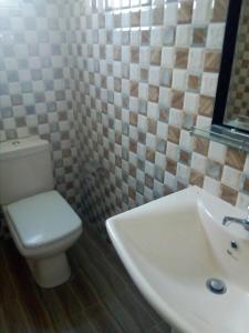 a bathroom with a white toilet and a sink at Nethmi Rooms in Negombo