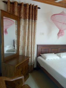 ein Schlafzimmer mit einem Bett und eine Kommode mit einem Spiegel in der Unterkunft Nethmi Rooms in Negombo