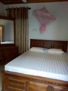 ein Schlafzimmer mit einem Bett mit einem rosa Regenschirm an der Wand in der Unterkunft Nethmi Rooms in Negombo