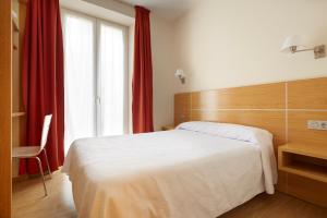 um quarto com uma cama branca e uma cortina vermelha em Musika Plaza em Zarautz