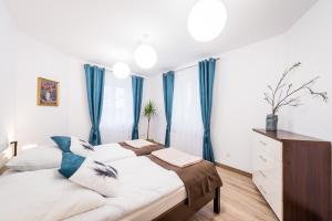 a bedroom with a large bed with blue curtains at Apartamenty Bosacka WAWELOFTS in Krakow