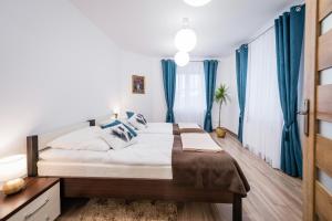 a bedroom with a large bed with blue curtains at Apartamenty Bosacka WAWELOFTS in Krakow