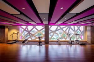 a gym with cardio machines in front of a large window at ASTON Ketapang City Hotel in Ketapang