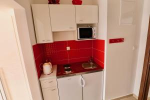 a small kitchen with white cabinets and red tiles at Meridiens in Dubrovnik