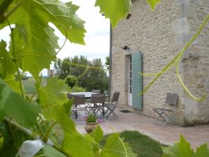 un patio avec une table et des chaises à côté d'un bâtiment dans l'établissement Gite Bacchus, à Baleyssagues