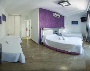 a bedroom with two beds and a purple wall at Hotel Molinos in Granada