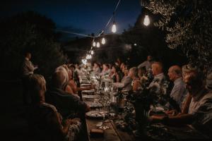 a group of people sitting at a long table at night at The Lazy Olive Villa - Podere Finerri in Asciano