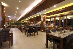 a restaurant with wooden tables and chairs and a bar at Crystal Lotus Hotel Yogyakarta in Yogyakarta