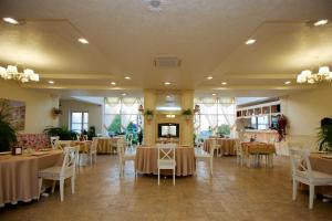 un salón de banquetes con mesas, sillas y ventanas en Hotel Alexandria, en Anapa