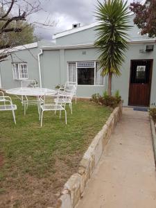 a table and chairs in the yard of a house at Oasis Shanti Backpackers in Oudtshoorn