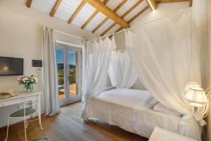 ein Schlafzimmer mit einem weißen Himmelbett und einem Fenster in der Unterkunft Tenuta Petra Bianca in Palau