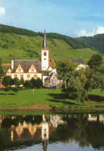 un gran edificio con una iglesia en una colina junto a un lago en Moselwinzerhaus, en Bruttig-Fankel