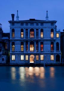 um grande edifício com as suas luzes acesas na água em Foresteria Levi em Veneza