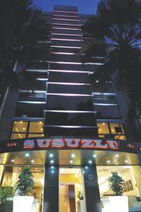 a tall building with a neon sign in front of it at Susuzlu Hotel in İzmir