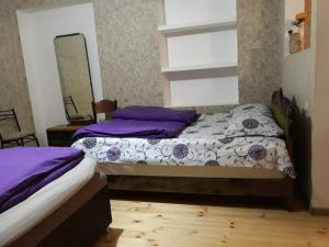 a bedroom with two beds with purple pillows and a mirror at Rati apartments in Tbilisi City