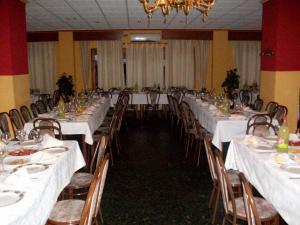 un salón de banquetes con mesas y sillas blancas y una lámpara de araña en Hotel Mulhacen, en Guadix