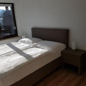 1 dormitorio con cama, ventana y mesita de noche en Apartments Krassnig, en Krumpendorf am Wörthersee