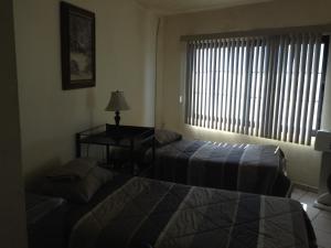a bedroom with two beds and a table and a window at Brisas 54632 in Monterrey