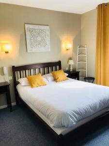 a bedroom with a large white bed with yellow pillows at l'auberge in Gamarde-les-Bains