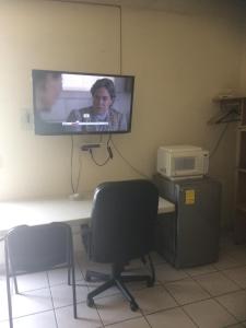 a television hanging on a wall with a desk and chairs at Brisas 54632 in Monterrey