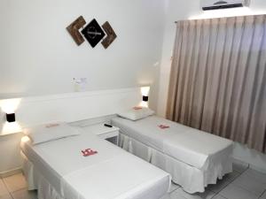 two beds in a room with a window at Hotel Planalto 2 in Governador Valadares
