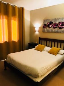 a bedroom with a bed with yellow pillows and a window at l'auberge in Gamarde-les-Bains