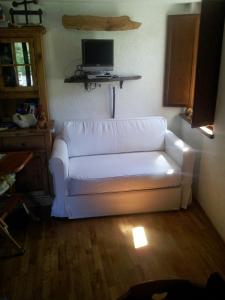 - un canapé blanc dans le salon doté d'une télévision dans l'établissement Appartamento in La Thuile località Thovex, à La Thuile