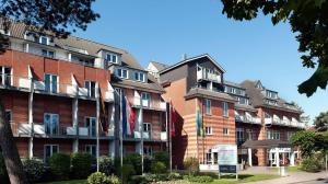 duży ceglany budynek z flagami przed nim w obiekcie Country Hotel Timmendorfer Strand w mieście Timmendorfer Strand