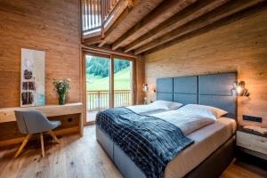 a bedroom with a bed and a desk and a window at LA SOA Chalets & Eventlodge in Schattwald