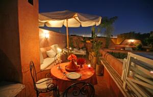 a table and chairs on a balcony with an umbrella at Riad Aloes & Spa in Marrakesh