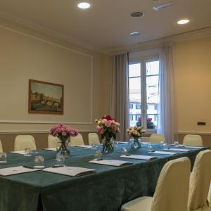 a conference room with a long table with flowers in vases at Hotel Bernini Palace in Florence