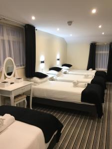 a hotel room with three beds and a mirror at Happy Return Hotel in Blackpool