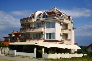 a tall white building with an umbrella in front of it at студия ЛИЛИЯ in Tsarevo