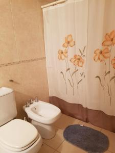 a bathroom with a toilet and a shower curtain with flowers at Juventus in Córdoba