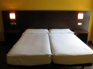 アモレビエタ・エチャノにあるEuba Hotelの2つの照明付きの部屋に白いベッド2台が備わります。