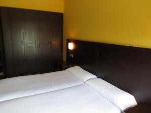 a bed with white sheets and a black headboard in a room at Euba Hotel in Amorebieta-Etxano